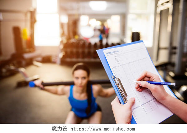 私人教练在蓝色剪贴板上写下合适女人的锻炼计划瑜伽普拉提